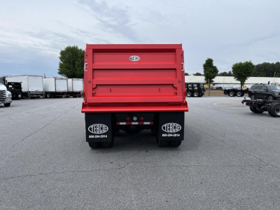 Rear view of red Western Star dump truck bed with TEBC logos on mud flaps, showing the tailgate and safety reflectors.