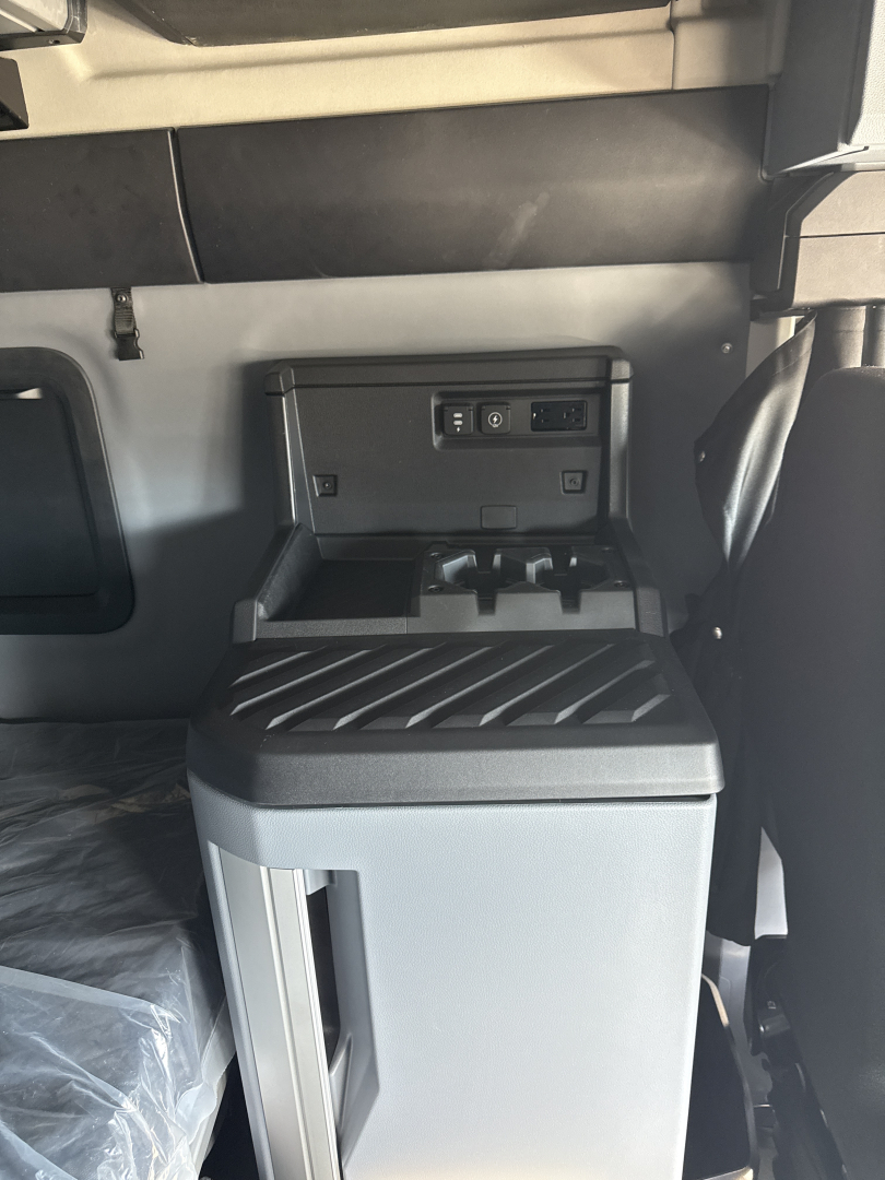 Cockpit area of a 2026 Mack PR64T76H truck showing center console with storage and USB/12V ports.