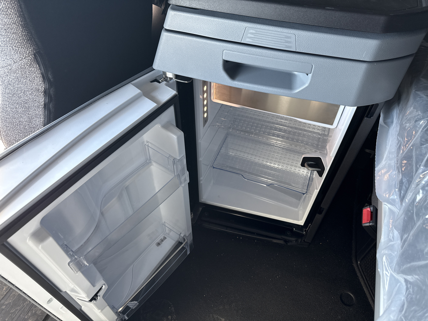 New Mack PR64T76H truck cab interior showing a compact under-dash refrigerator with open door and empty freezer shelf.