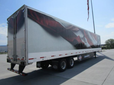Trailer with triple axle on a paved lot, reflective silver side panels, rear doors openable, utility van style trailer.