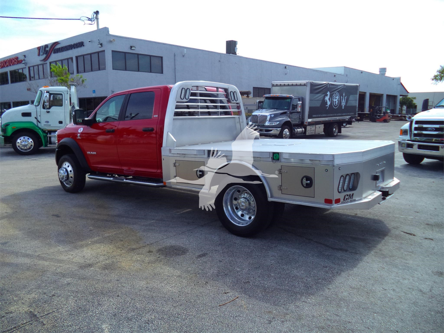 Ram 5500 pickup with red cab and aluminum flatbed, side toolboxes visible, flatbed rear and chrome wheels.