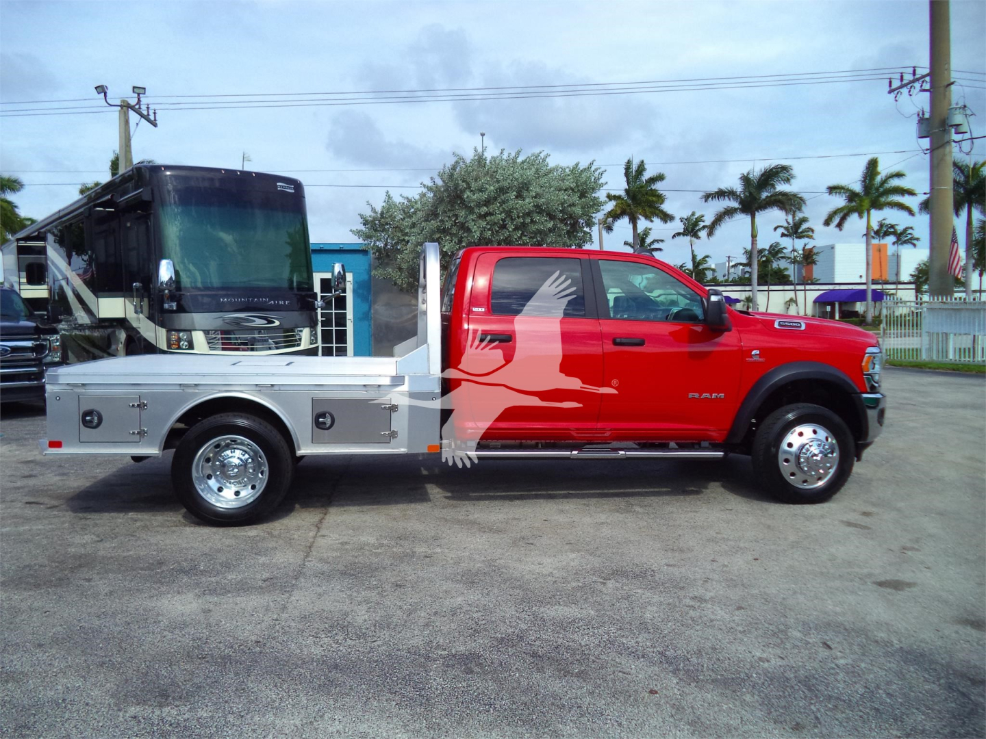 Ram 5500 SLT pickup with flatbed and utility compartments, side view showing chrome wheels, dual rear wheels, black cab windows, and silver flatbed with built-in storage.