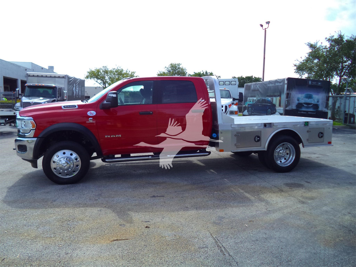 2024 Ram 5500 SLT dual rear wheel pickup with flatbed and utility toolbox, side view showing red cab and silver flatbed.