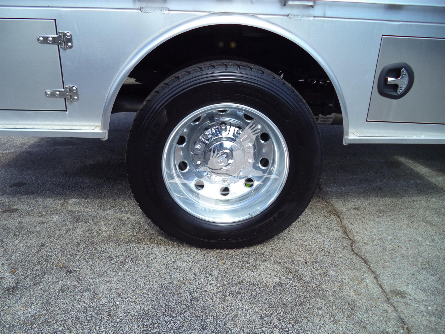 Ram 5500 SLT flatbed truck wheel and chrome hubcap showing tire and truck body panel details.