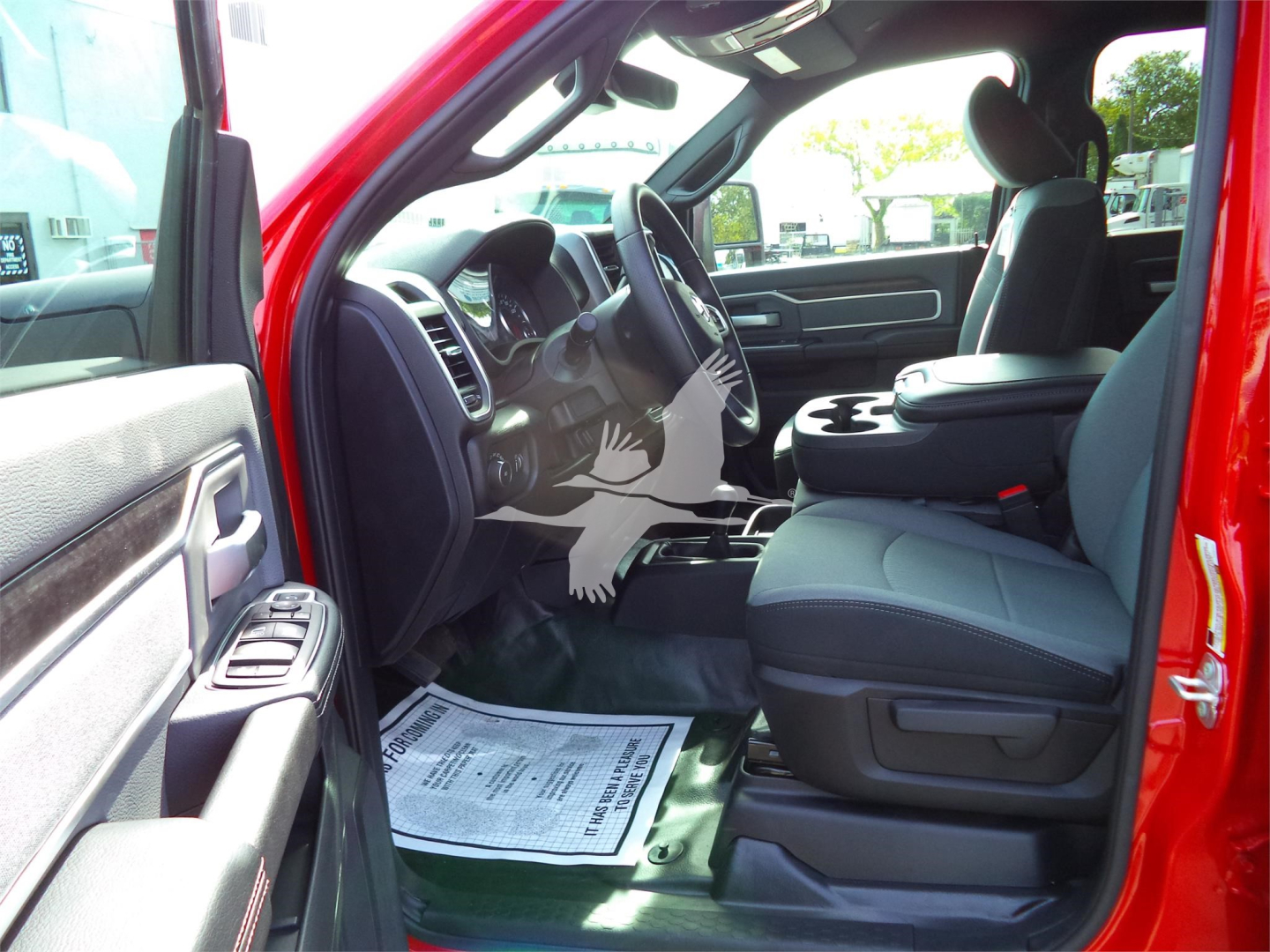 Interior of red Ram 5500 SLT crew cab showing front seats and dashboard from the driver’s side with open door; center console and floor mat visible.