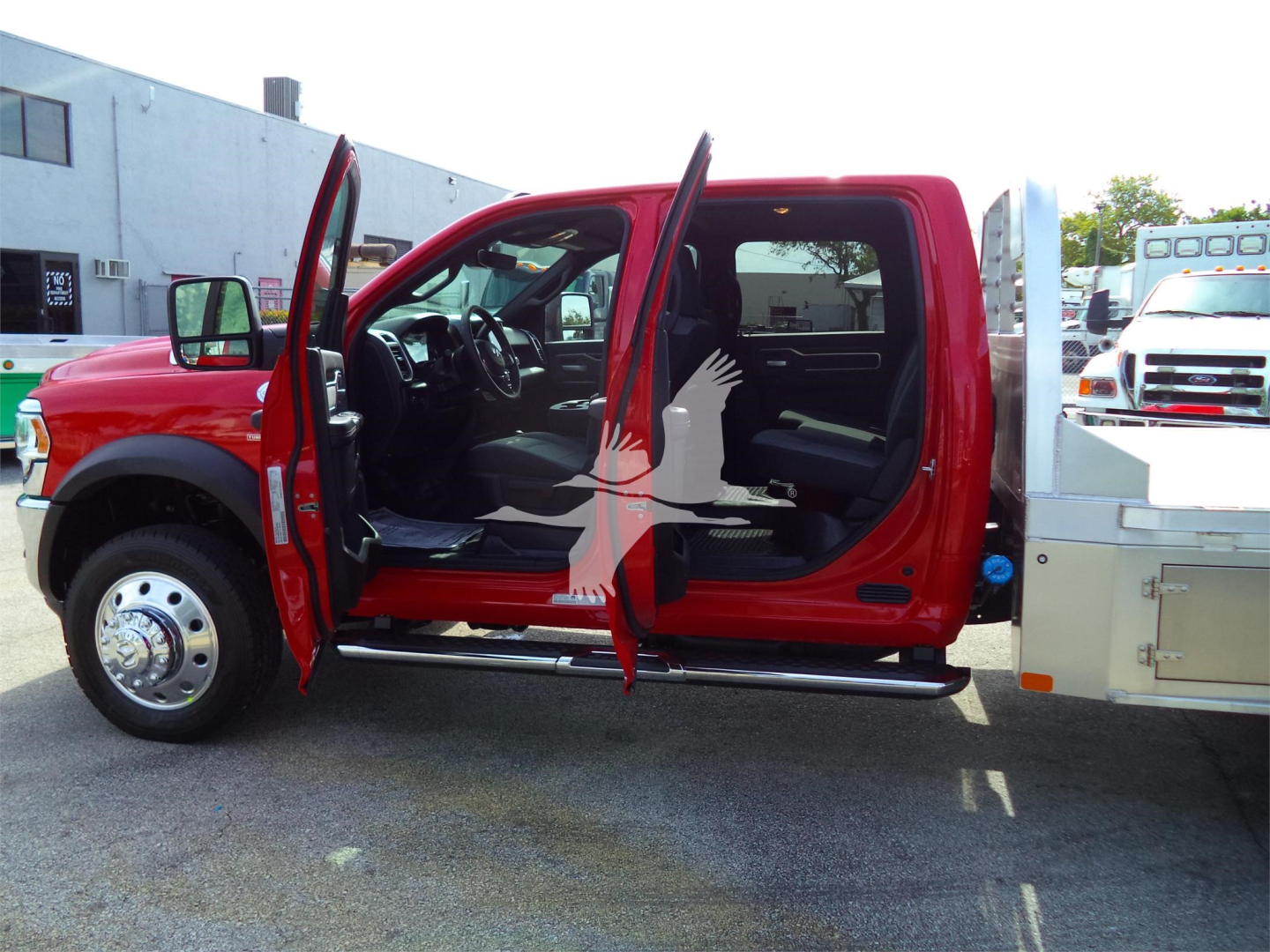 Ram 5500 SLT truck side view with front and rear doors open showing interior cabin and steps, red exterior, flatbed rear with chrome wheel well, stock number RAM5500LALSKCM.