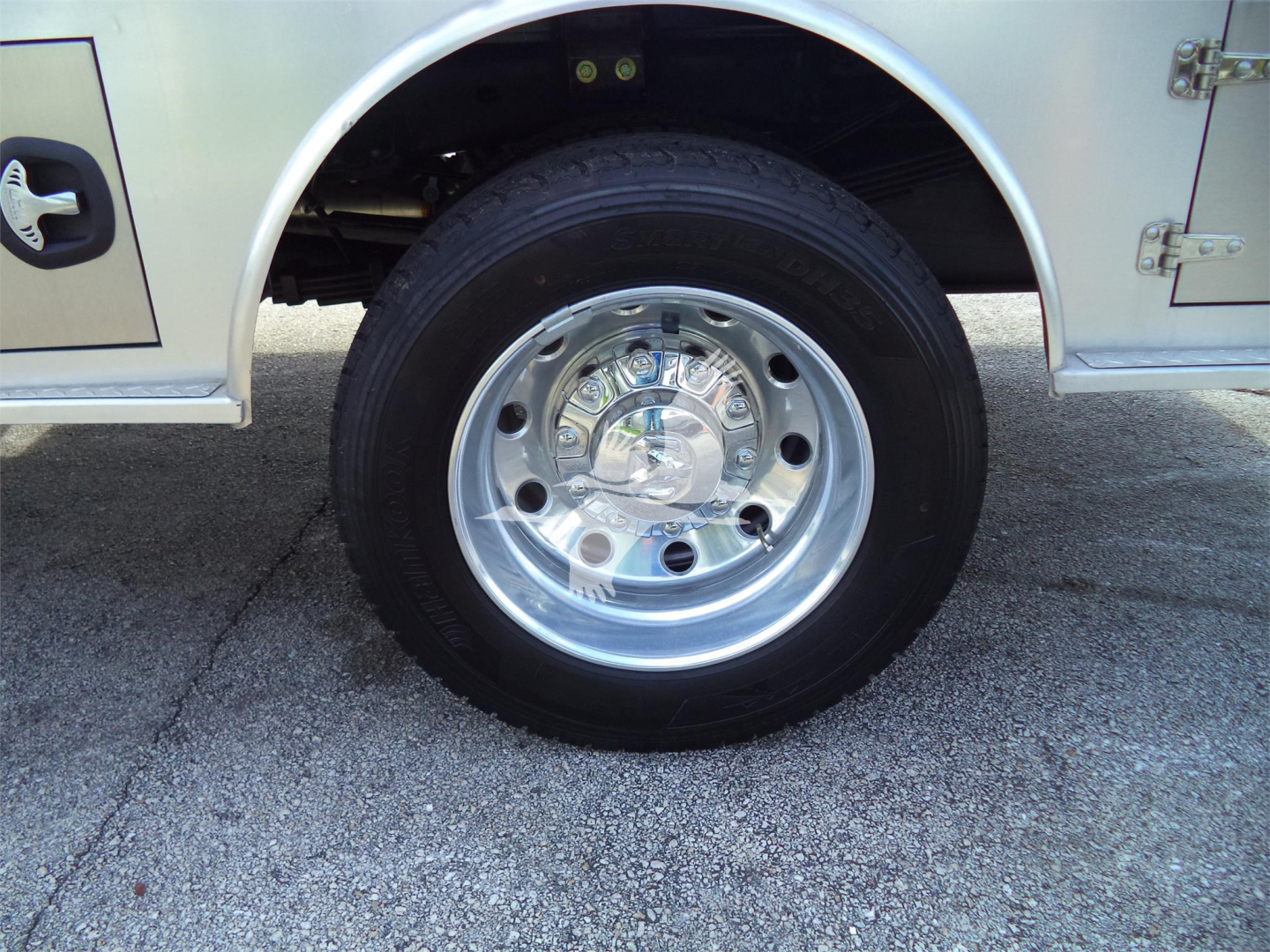 Wheel close-up on Ram 5500 SLT flatbed truck showing chrome steel wheel and tire, with silver body panel and mudguard visible.