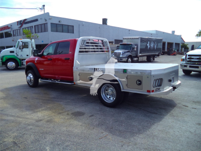 Ram 5500 pickup with red cab and aluminum flatbed, side toolboxes visible, flatbed rear and chrome wheels.