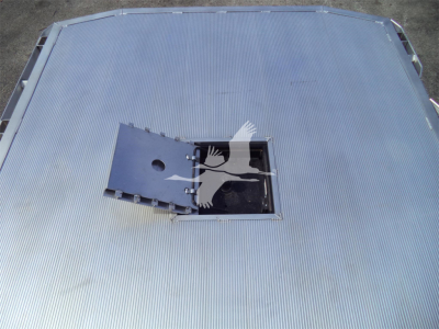 Flatbed truck bed with a recessed tool/storage hatch open, showing a metal panel and hatch opening on a Ram 5500 flatbed.