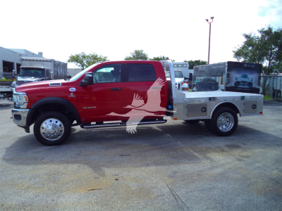 2024 Ram 5500 SLT dual rear wheel pickup with flatbed and utility toolbox, side view showing red cab and silver flatbed.