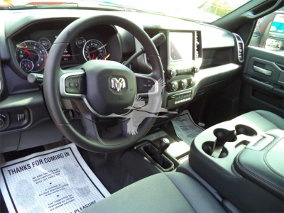 Interior view of a 2024 Ram 5500 SLT showing steering wheel with RAM emblem, center console with touchscreen, air vents, and dashboard gauges.