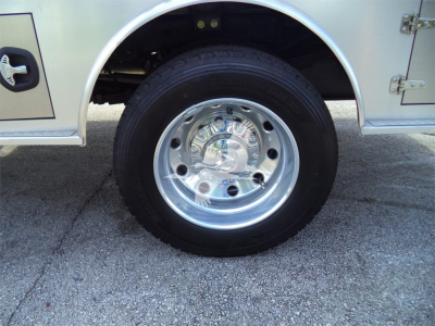 Wheel close-up on Ram 5500 SLT flatbed truck showing chrome steel wheel and tire, with silver body panel and mudguard visible.
