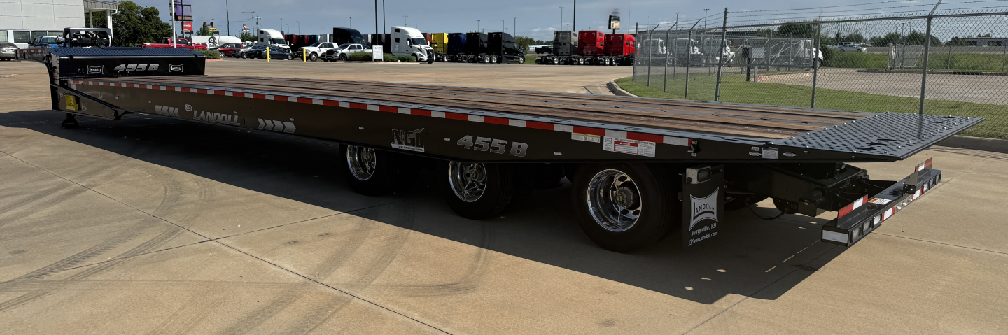 Landoll 455B-53 55 ton traveling axle lowboy trailer showing long flatbed and rear ramps with wheels and reflective stripe