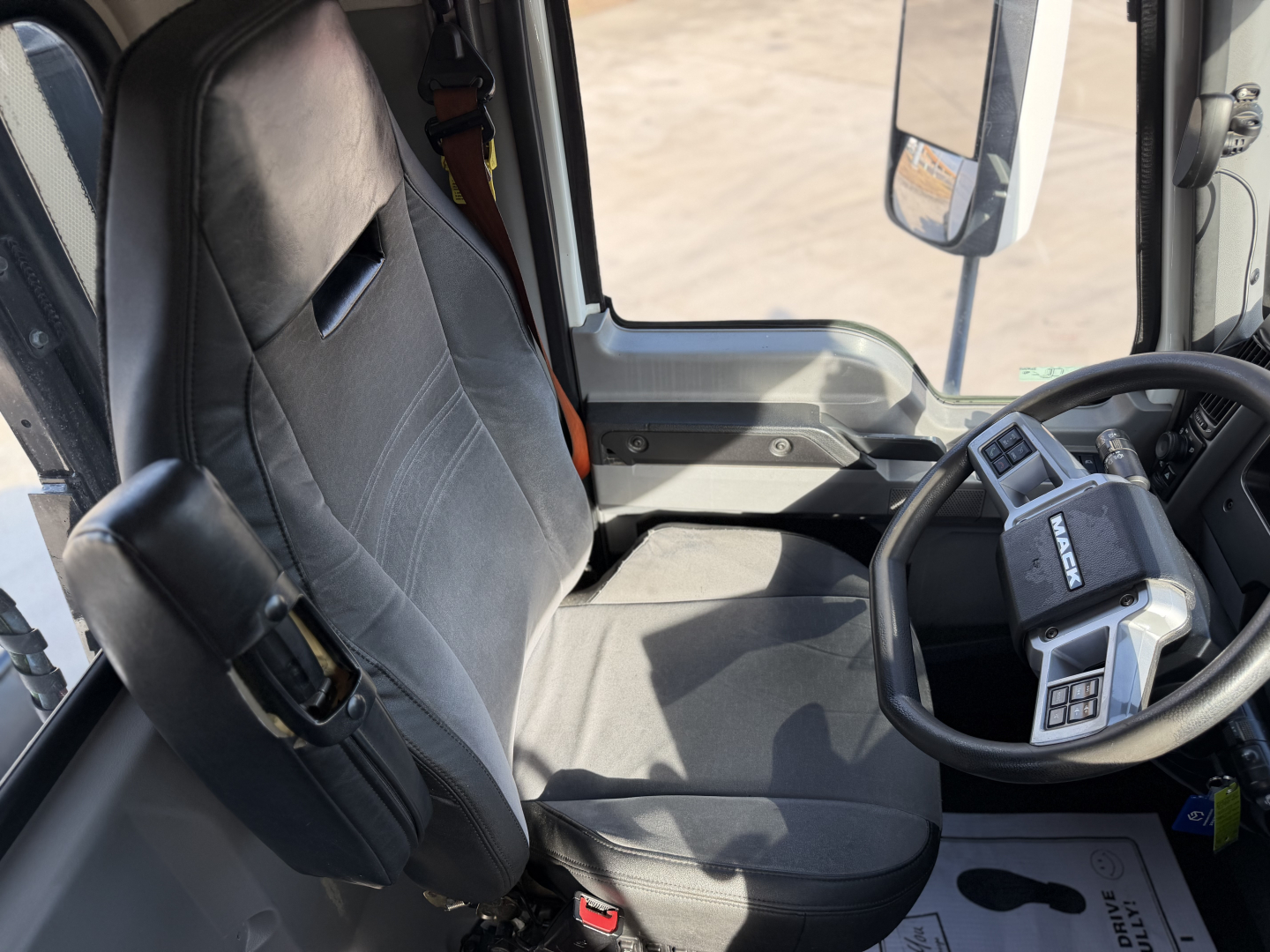 Truck cab interior of a 2023 Mack ANTHEM 64T showing the driver seat, steering wheel, and dashboard in view.