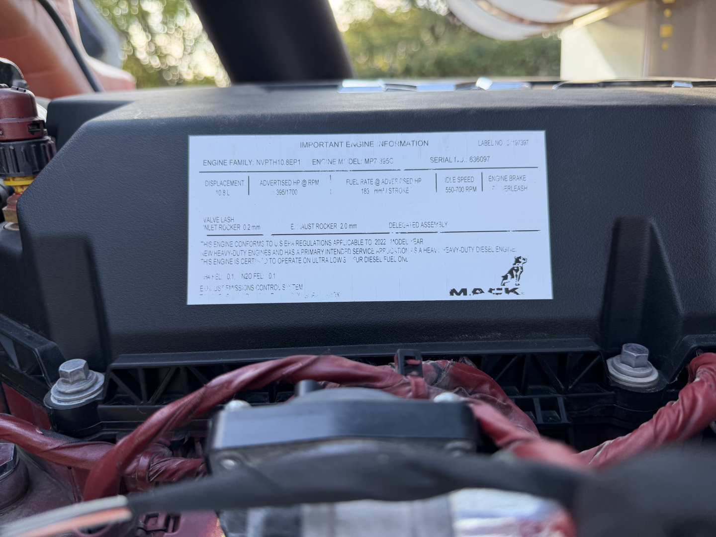 Engine data label on Mack ANTHEM 64T with VIN sticker and wiring harness; label contains engine family and serial numbers, plus a diagram of engine components.