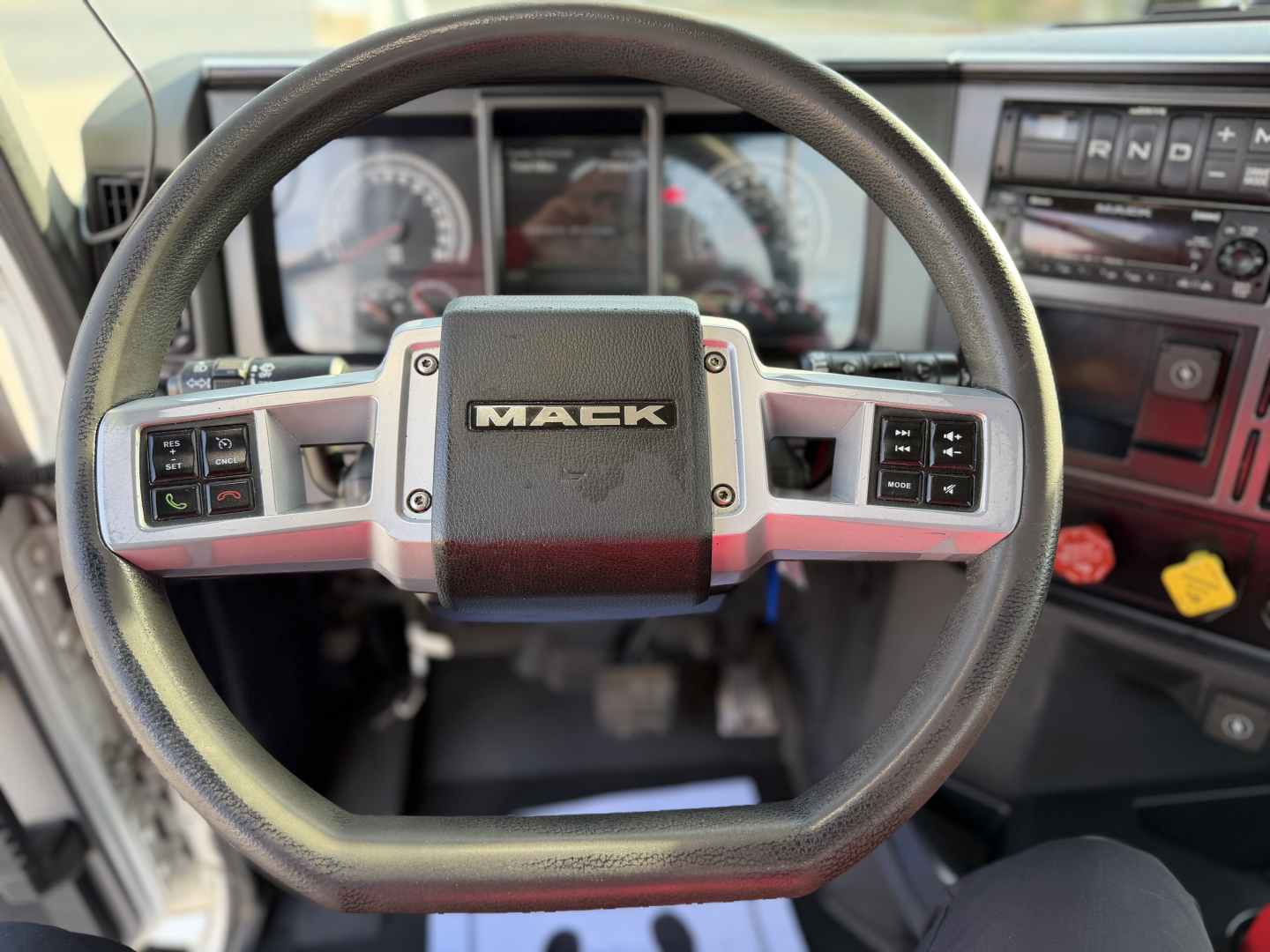 Steering wheel interior of a Mack truck showing the center badge and dashboard controls