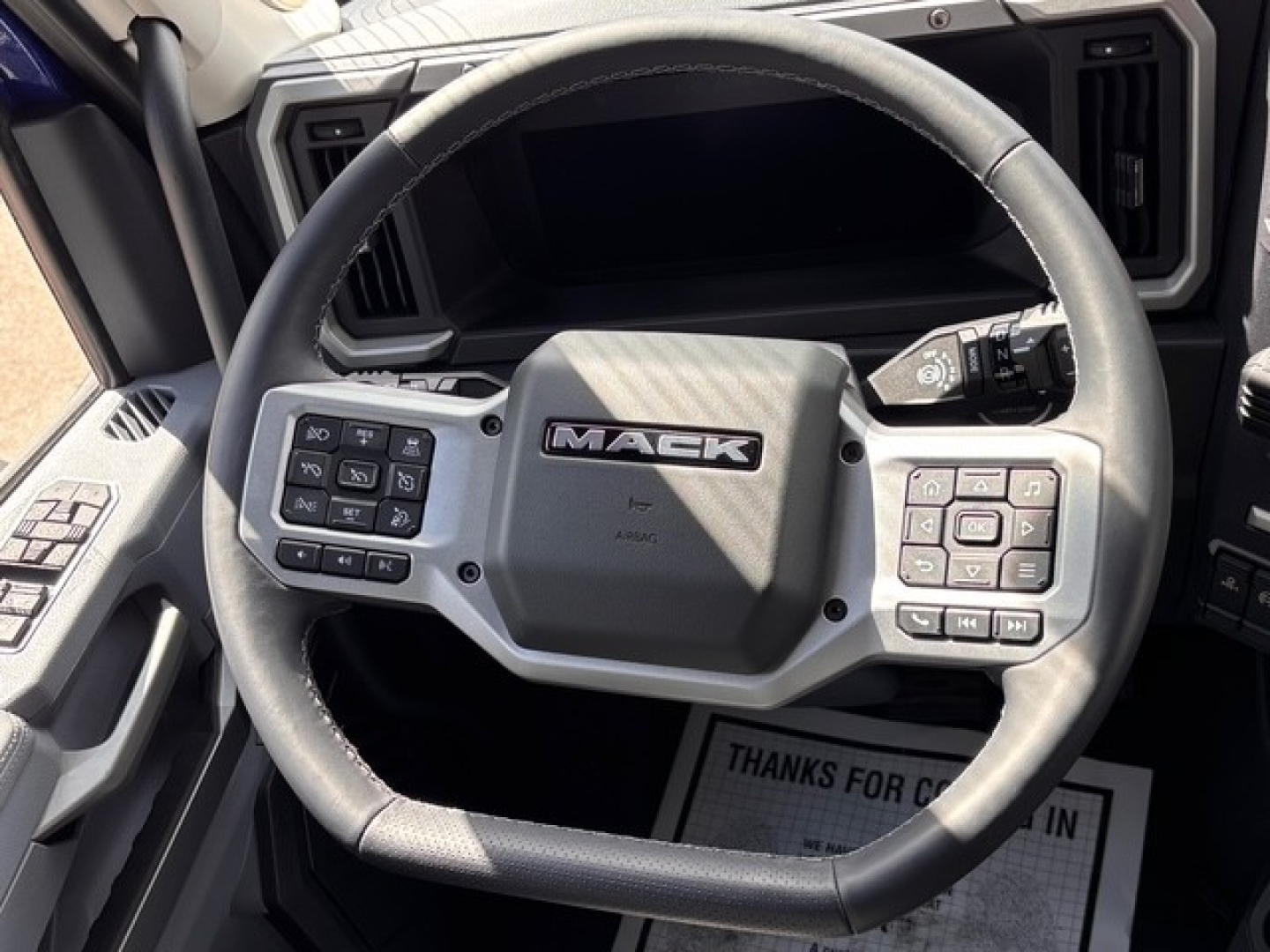 Mack PR64T76H truck interior steering wheel with control buttons and dashboard visible.