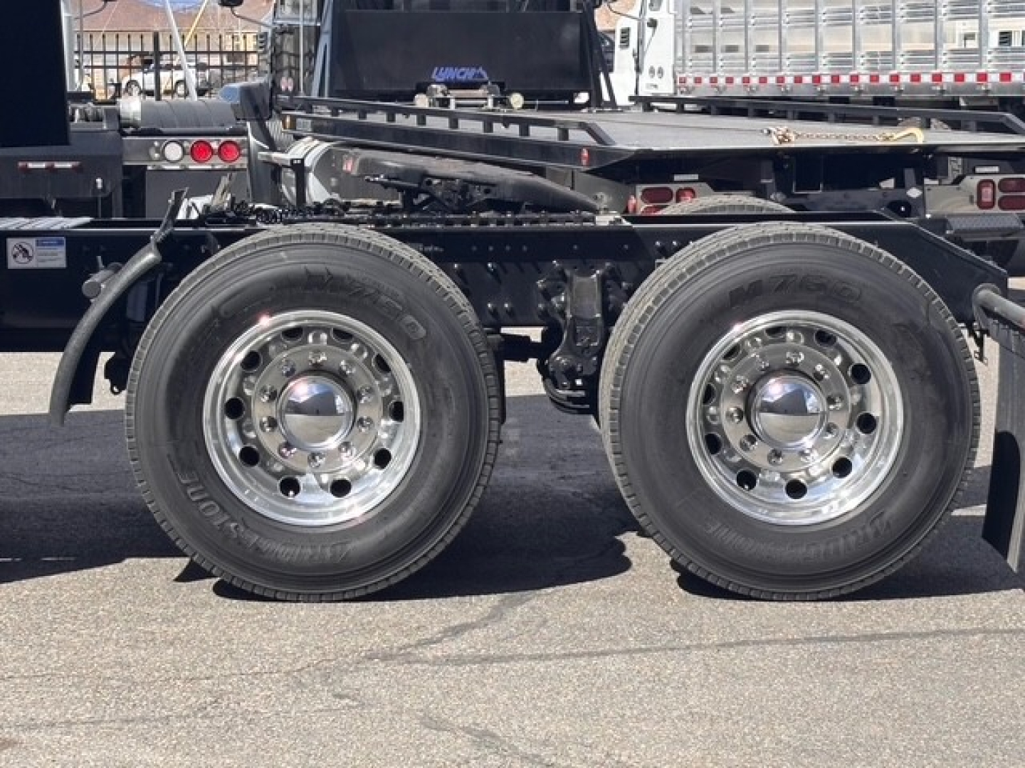 Mack PR64T76H truck chassis with dual rear axles and polished steel wheels; visible suspension and frame components.
