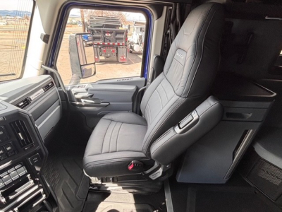 Cab interior of a 2026 Mack PR64T76H showing driver seat, steering wheel area, and dash in the cab.