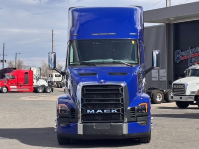 Truck front view showing Mack grille with large chrome bumper and blue cab; text 'MACK' on grille, truck hood, side mirrors, and blue sleeper cab.