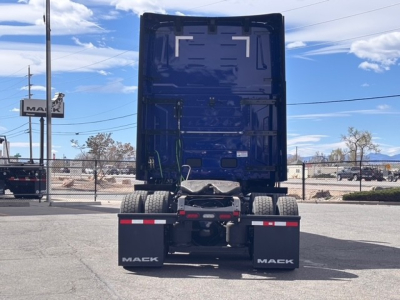 Rear view of a blue Mack PR64T76H tractor showing dual rear mud flaps with 'MACK' logos, fifth wheel and rear axle components visible.