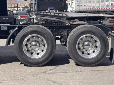 Mack PR64T76H truck chassis with dual rear axles and polished steel wheels; visible suspension and frame components.