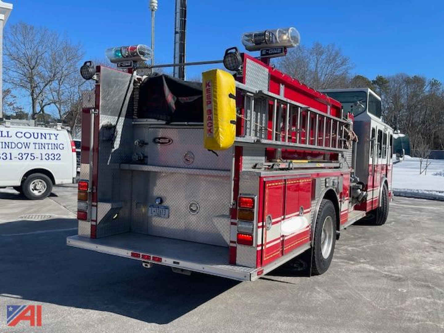 Emergency One Cyclone Pumper fire truck rear view showing rear compartments, hoses, and equipment with ladder rack.