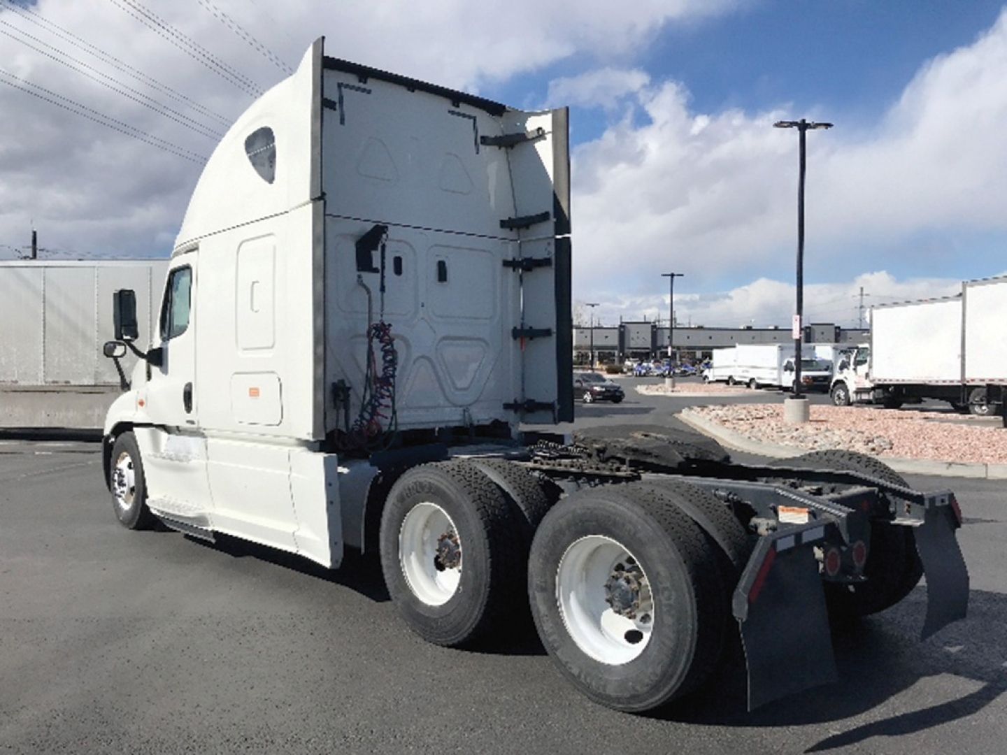 Truck chassis of a Freightliner Cascadia125 Evolution semi-truck sleeper cab viewed from the rear-left, with dual rear axles and fifth-wheel hitch area visible.