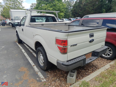 Ford F-150 pickup truck with a bed rack and toolbox, white color, 2013 model, in a parking lot.