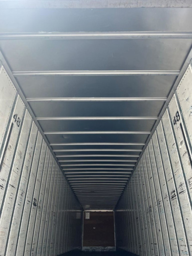 Interior of a utility van trailer cargo area with ribbed metal walls and ceiling, showing numbered panels along the sides.