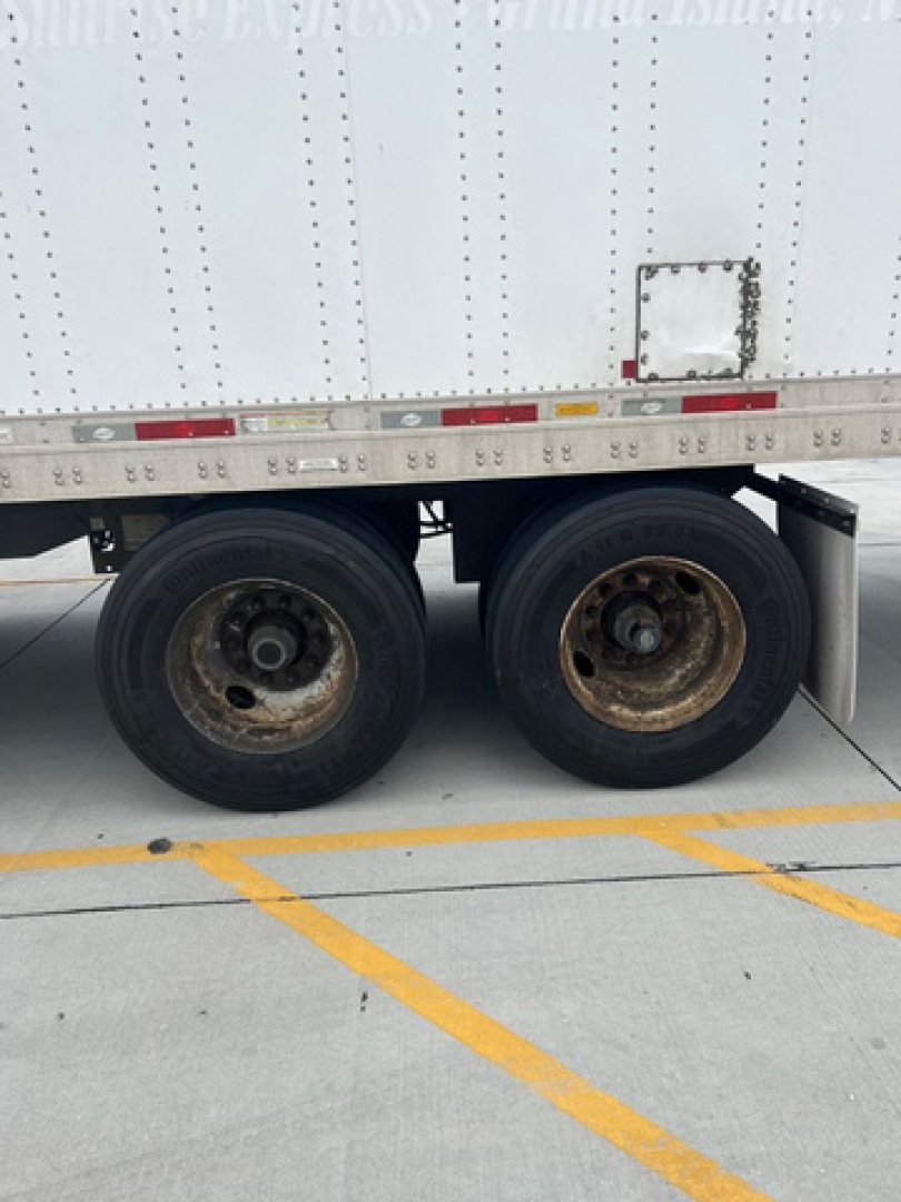Trailer wheel area of a 2014 Utility Van showing dual rear axles with black tires and rusted wheel hubs; no legible branding or model text visible.