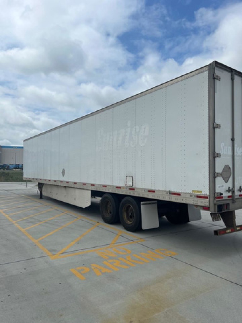 Trailer side view showing a long white utility trailer with tandem axles