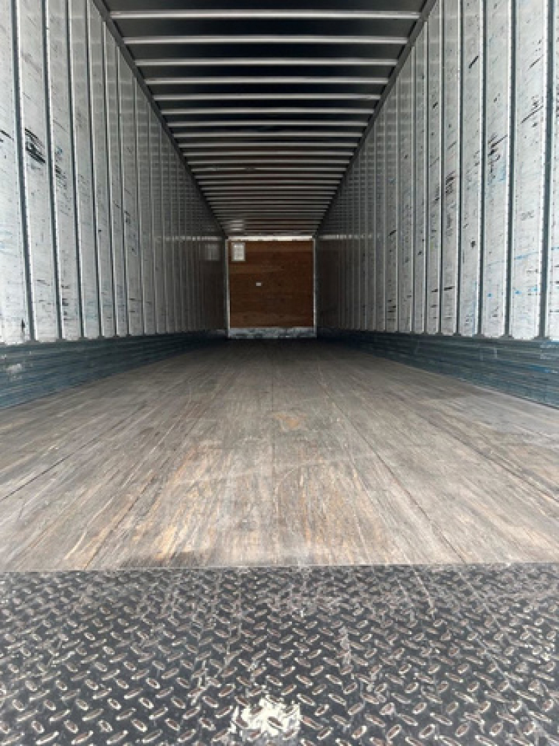 Empty Utility van trailer interior with wood floor and metal walls, rear doors, no visible labels or numbers.