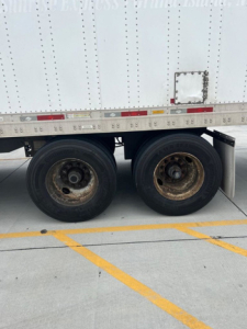 Trailer wheel area of a 2014 Utility Van showing dual rear axles with black tires and rusted wheel hubs; no legible branding or model text visible.