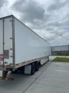 Trailer side view of a white utility van trailer with tandem axles.