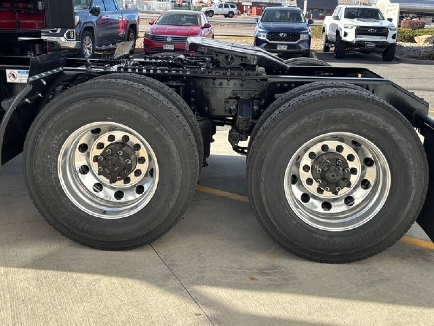 Front side view of a Mack PR64T76H semi truck chassis showing dual rear axles with polished aluminum wheels and large tires.