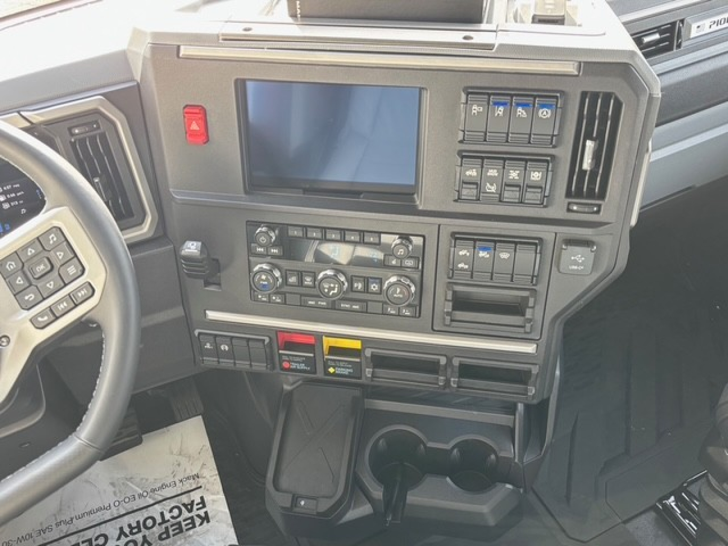 Dashboard of a Mack truck cab showing control panel, touchscreen display, climate controls, and switches.