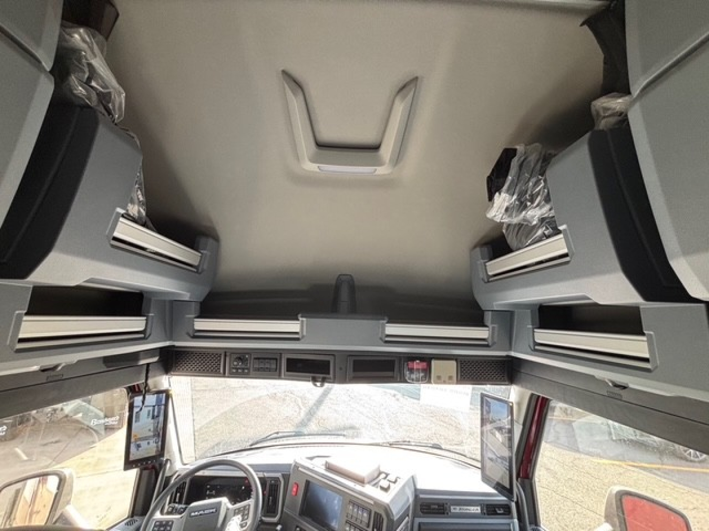 In-cab view of a 2026 Mack PR64T76H truck showing overhead sleeper storage compartments and dashboard with multiple control panels.