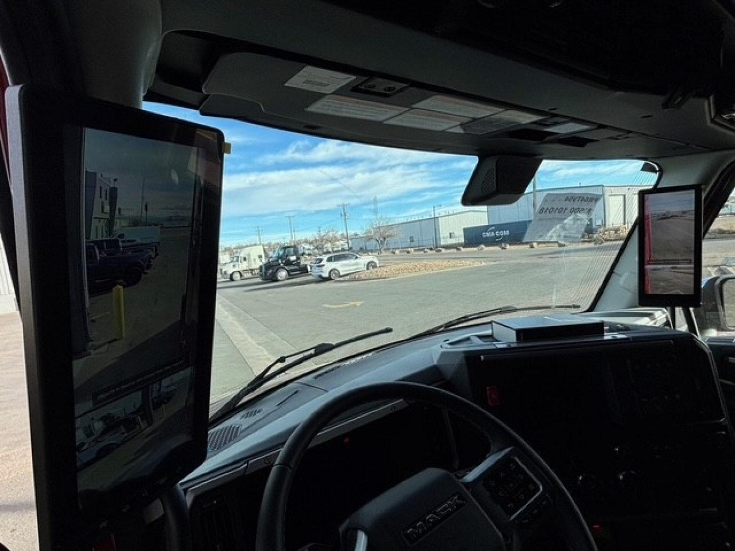 Mack PR64T76H truck cabin interior showing large vertical screen monitor on driver side and dashboard controls.