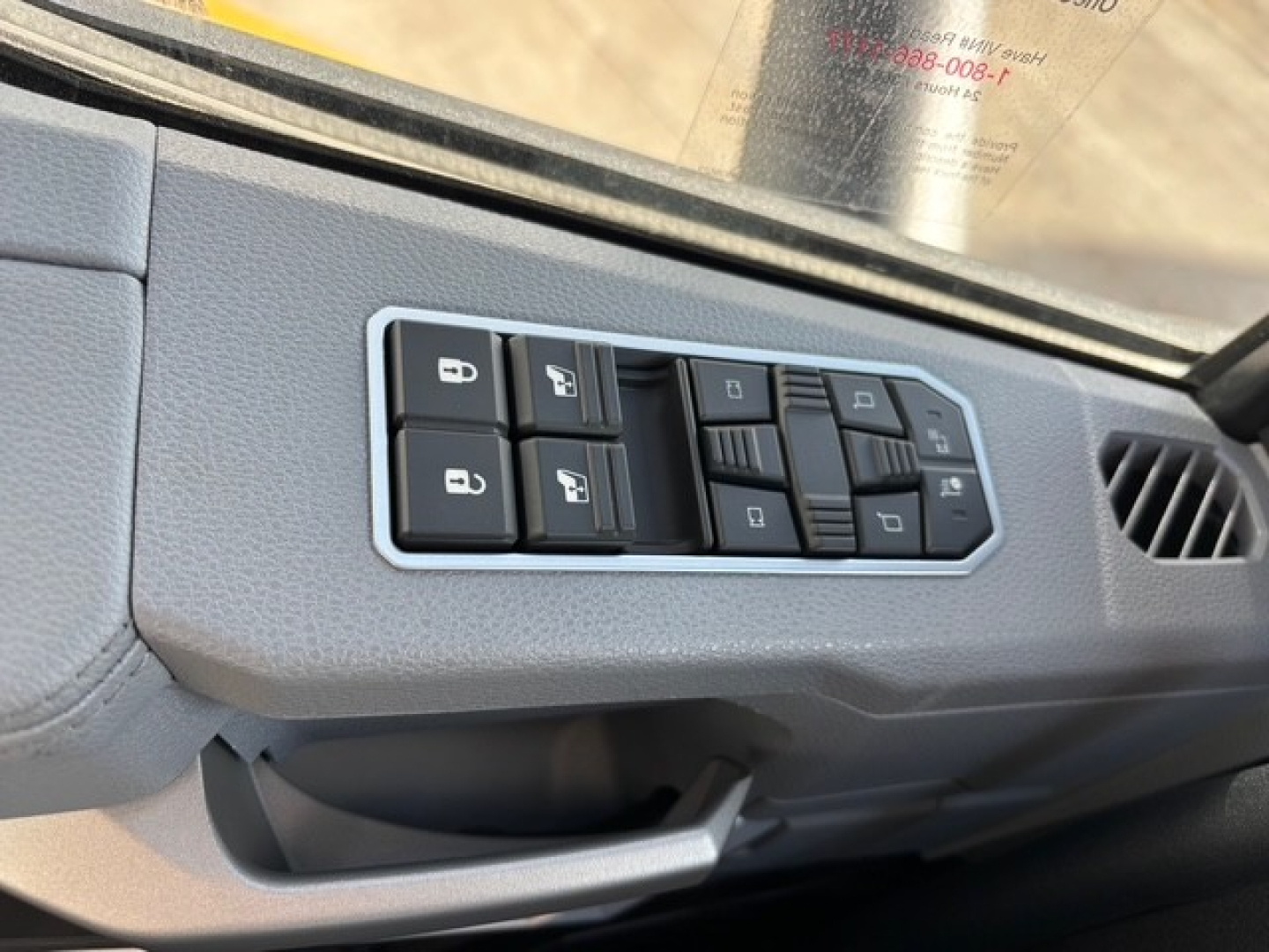 Interior door panel with window and mirror control switches in a Mack PR64T76H cab.
