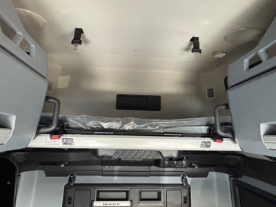 Mack truck cab interior showing sleeper area with bunk bed and overhead cabinets; label visible near bed area and dashboard area below.
