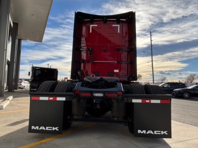 Mack PR64T76H truck rear view showing dual rear wheels, red cab, black fenders with Mack branding mud flaps, and fifth-wheel area.
