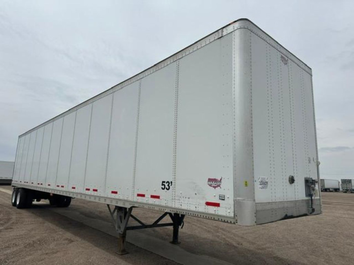 Trailer side view showing a white 53' Wabash van trailer with dual rear axles and front underride area visible.