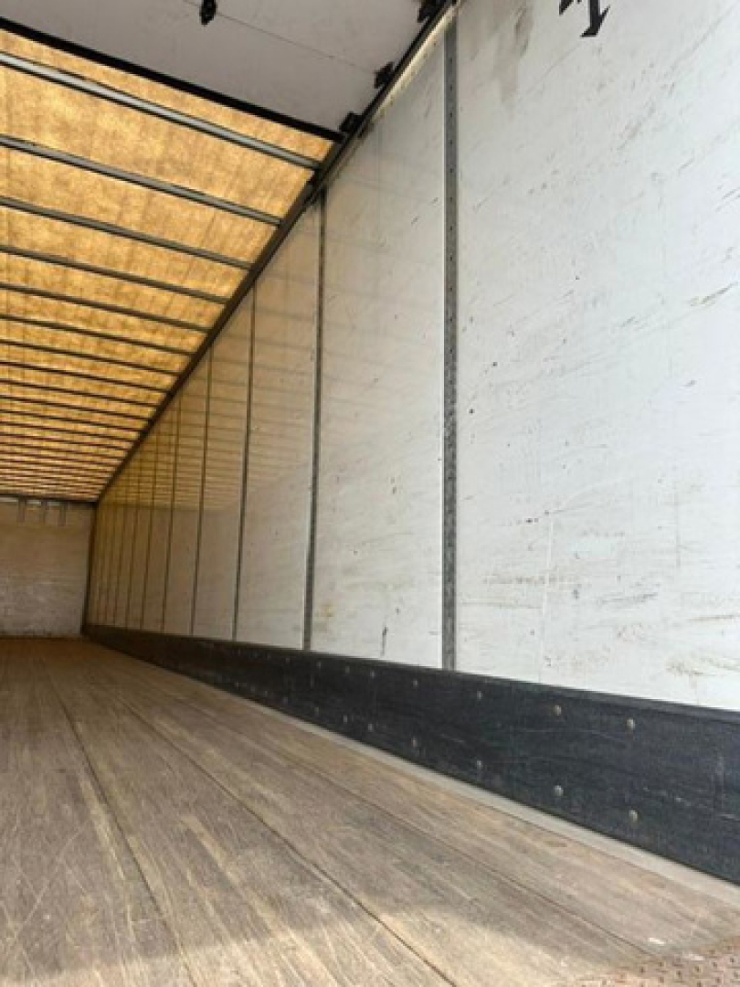 Van trailer interior showing wooden floor and white side walls with black base rail.