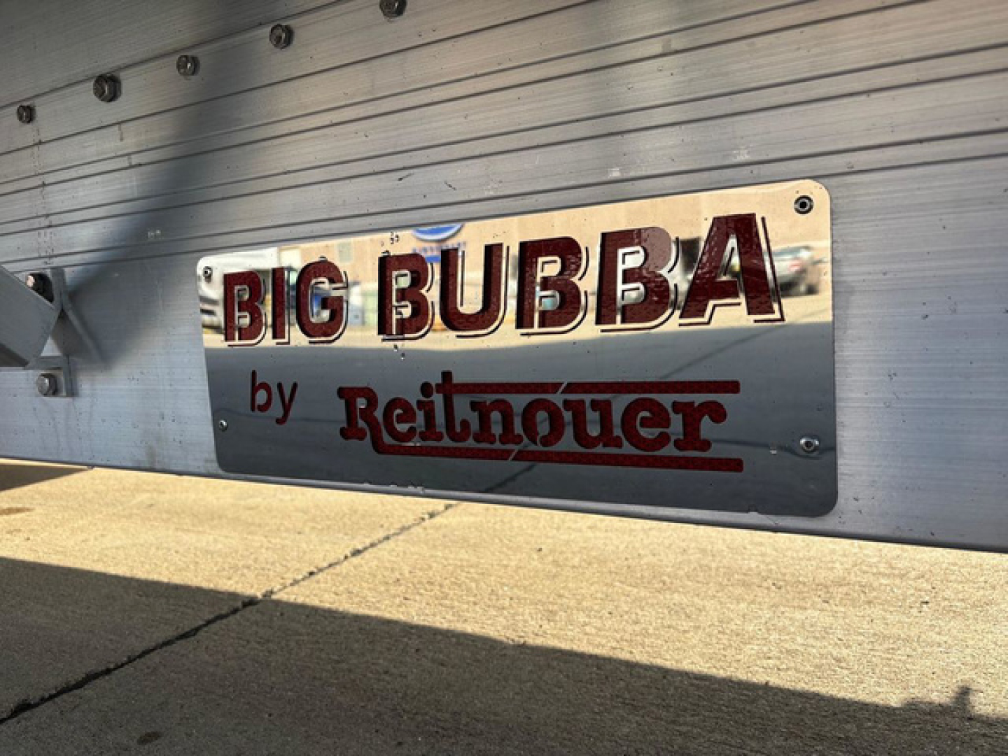 Trailer side with 'BIG BUBBA by Reitnouer' branding plate mounted on dropdeck trailer.