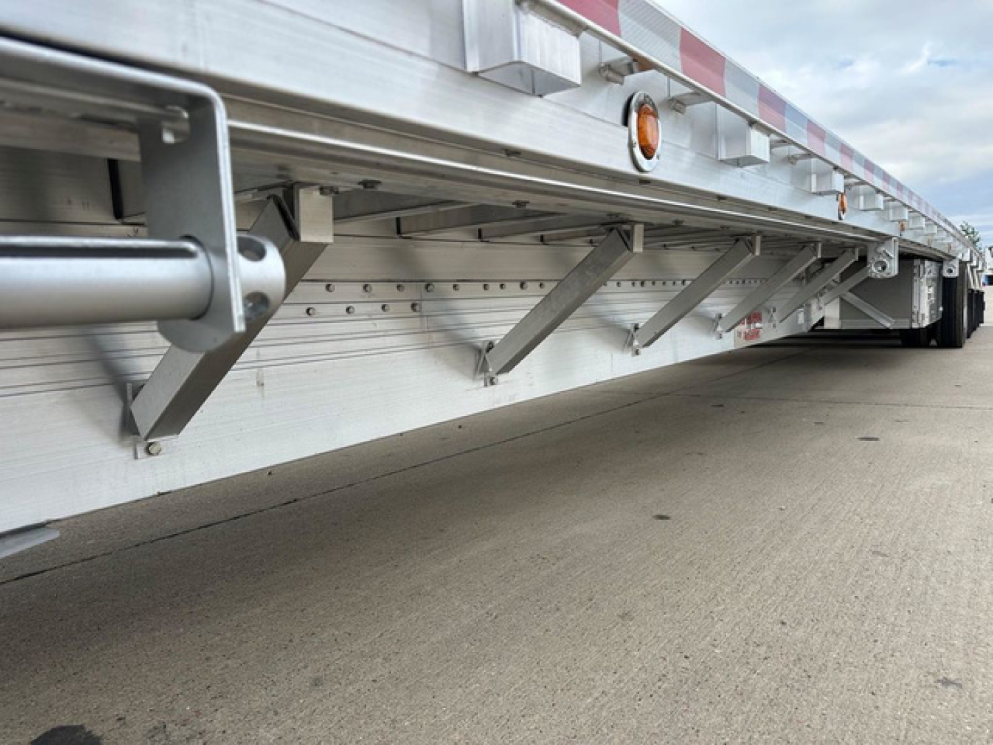 Dropdeck trailer side view showing structural brackets and aluminum side rail with reflectors.