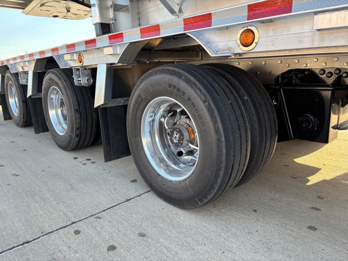 Dropdeck trailer wheel area showing dual rear axles and polished rims with tire treads visible.