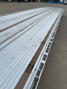 Dropdeck trailer deck showing aluminum planks with wooden strips and side stake pockets.