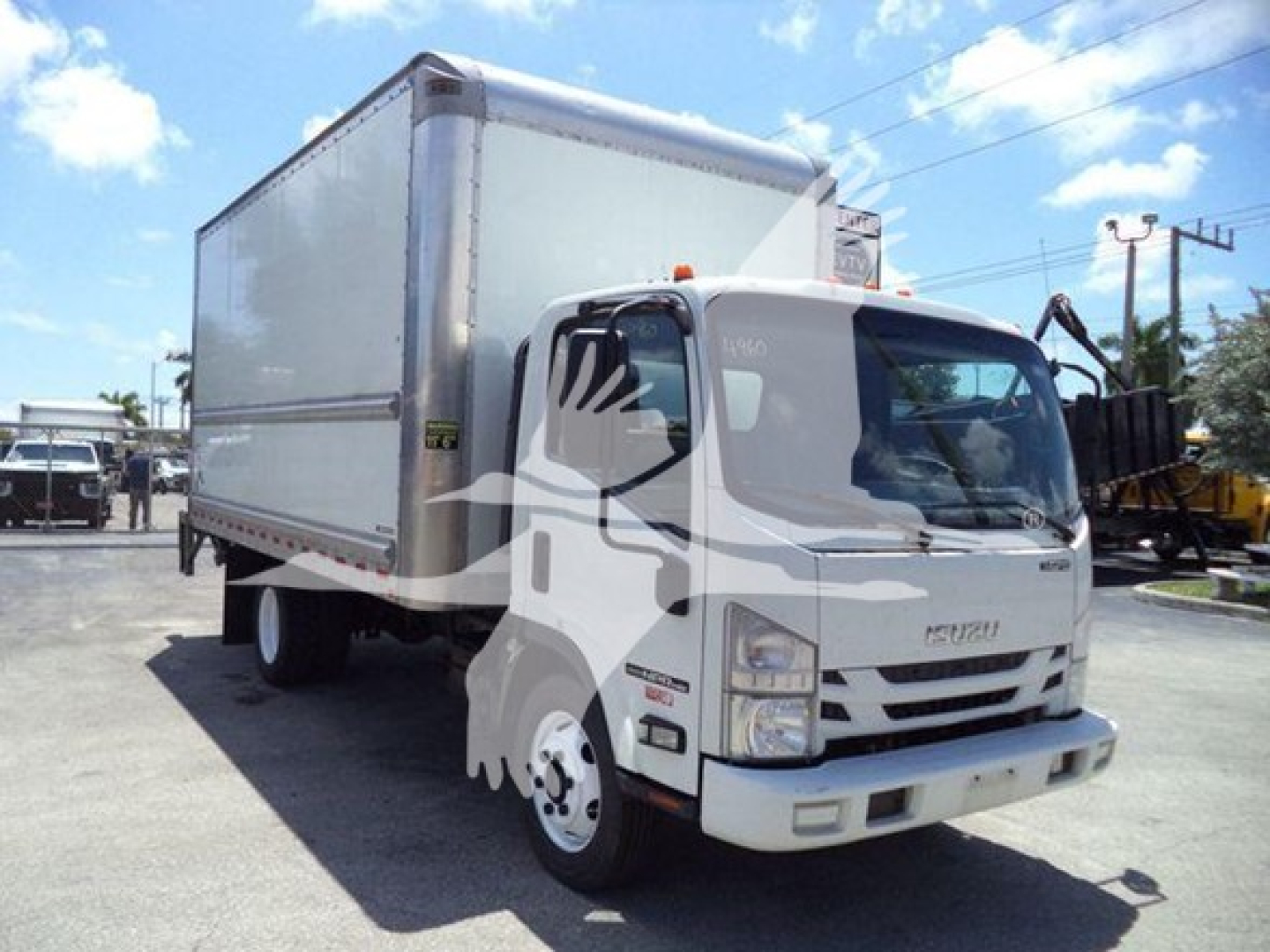 Isuzu NPR box truck in a dealership lot with white cab and box, front three-quarter view. Visible text: Isuzu emblem on grille; no other legible labels.