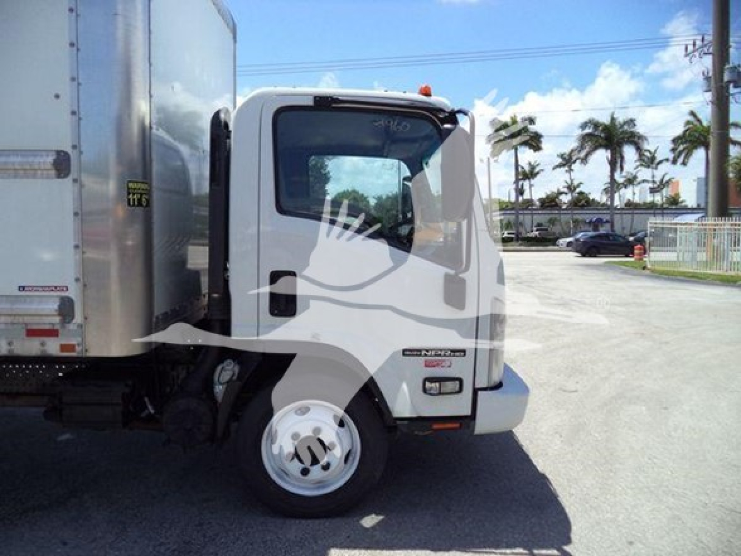Isuzu NPR box truck cab side view showing front wheel and door area with a white cab and cargo box attached.